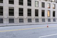 two orange cones are on the side of a city street while a man is riding a bicycle