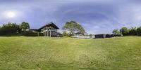 the reflection of the home from the grass field, with houses behind it and trees in the background