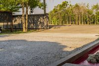 a dog relaxing on the edge of a concrete pool and its head down the side, next to a wooded area, with many trees