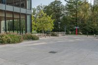 a building next to a sidewalk with trees in the background and benches on each side