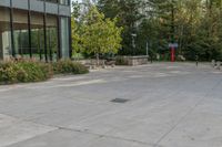 a building next to a sidewalk with trees in the background and benches on each side