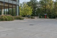 a building next to a sidewalk with trees in the background and benches on each side