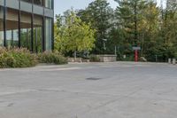 a building next to a sidewalk with trees in the background and benches on each side