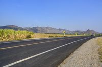 three yellow and white signs near a highway with mountains in the background in front of them