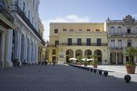 three young people are walking down a city square in front of old buildings and palm trees