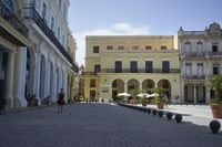 three young people are walking down a city square in front of old buildings and palm trees
