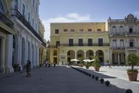 three young people are walking down a city square in front of old buildings and palm trees