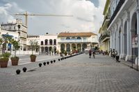 three young people are walking down a city square in front of old buildings and palm trees