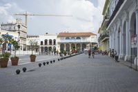 three young people are walking down a city square in front of old buildings and palm trees