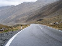 an empty road with a mountain behind it and a few signs at the top of the street