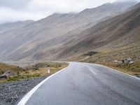 an empty road with a mountain behind it and a few signs at the top of the street