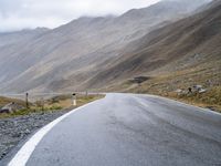 an empty road with a mountain behind it and a few signs at the top of the street