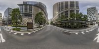 two wide angle roads with traffic and several buildings in the background of the image