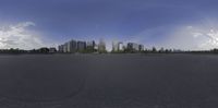 a parking lot full of cars and trees near some buildings and a sky line with white clouds