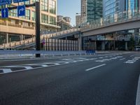 an empty road with a street sign at the curb in front of an office building