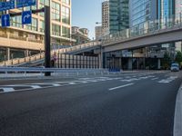 an empty road with a street sign at the curb in front of an office building