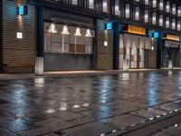 a large brick sidewalk with a store front at night time and a sign that says