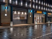 a large brick sidewalk with a store front at night time and a sign that says