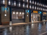 a large brick sidewalk with a store front at night time and a sign that says