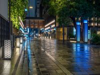 a large brick sidewalk with a store front at night time and a sign that says