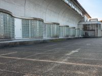 two empty parking spaces with two empty doors and a large window on the wall between two buildings