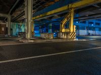 the car is parked underneath an overpass at night time, while no other cars are present