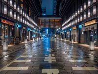 a large brick sidewalk with a store front at night time and a sign that says