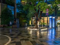 a large brick sidewalk with a store front at night time and a sign that says