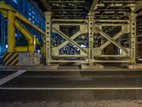 the car is parked underneath an overpass at night time, while no other cars are present