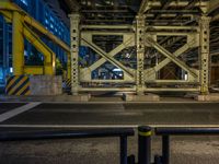 the car is parked underneath an overpass at night time, while no other cars are present