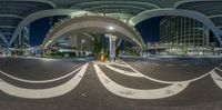 a street intersection with arches leading into a busy city at night with street lights on