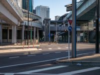 an empty road with a street sign at the curb in front of an office building