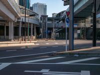 an empty road with a street sign at the curb in front of an office building