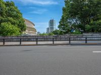 a view of a stadium from the street, showing many trees and bushes in the distance