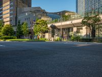 an empty road with a street sign at the curb in front of an office building