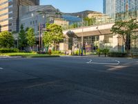 an empty road with a street sign at the curb in front of an office building