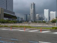 a picture of the skyline in tokyo with a highway crossing and an orange traffic cone in foreground