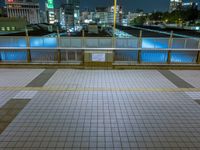 people standing on a subway platform with many buildings in the background at night light in tokyo