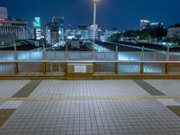 people standing on a subway platform with many buildings in the background at night light in tokyo