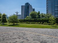 a wide brick road next to a tall buildings with a clock tower in the distance