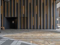 a walkway leading up to a wooden wall next to a cement area with floor tiles