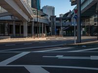 an empty road with a street sign at the curb in front of an office building