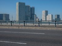 the highway and bridge leading to a city in japan and has tall buildings and blue skies