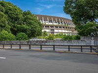 a view of a stadium from the street, showing many trees and bushes in the distance