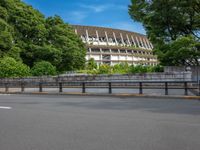 a view of a stadium from the street, showing many trees and bushes in the distance