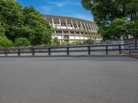 a view of a stadium from the street, showing many trees and bushes in the distance