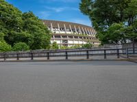 a view of a stadium from the street, showing many trees and bushes in the distance