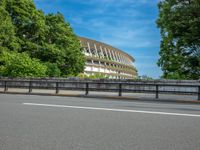 a view of a stadium from the street, showing many trees and bushes in the distance