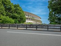 a view of a stadium from the street, showing many trees and bushes in the distance