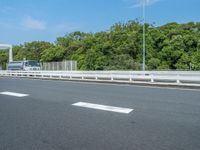 a semi truck driving down an empty highway with trees in the background at daytime,